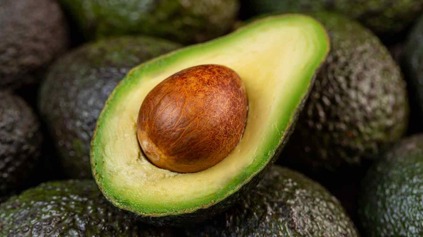 Gesneden avocado bovenop avocado's. 